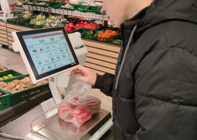 Mężczyzna dokonuje ważenia warzyw w supermarkecie.