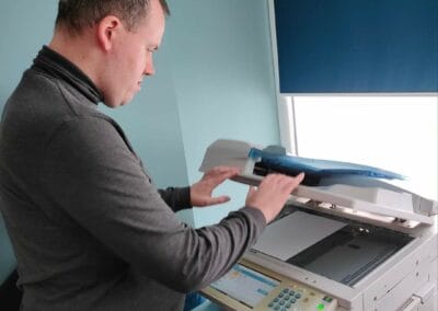 Mężczyzna przytrzymuje część urządzenia wielofunkcyjnego w celu dokonania skanowania.