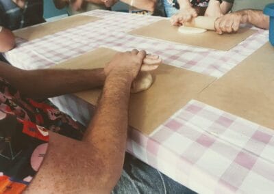 Częściowo ukazane osoby wyrabiają masę solną na stole.