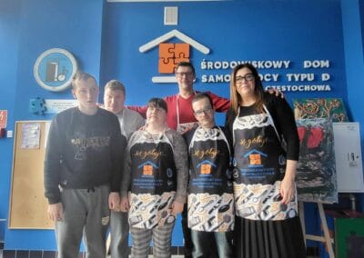 Sześć osób obejmując się pozuje do zdjęcia.