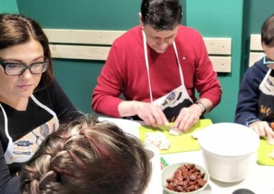 Dwaj mężczyźni kroją kurczaka. Dwie kobiety rozmawiają.