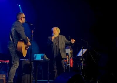 Andrzej Grabowski śpiewa na scenie razem z Krzysztofem Niedźwieckim. Krzysztof Niedźwiecki gra na gitarze.