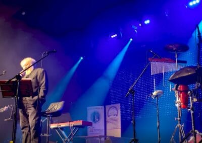 Andrzej Grabowski śpiewa na scenie w towarzystwie dwóch muzyków.