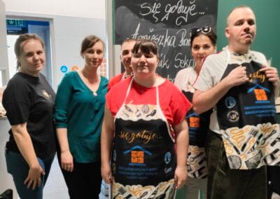 Sześć osób pozuje do zdjęcia. Dwoje uczestników ubranych jest w fartuchy kulinarne.