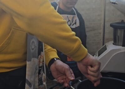 Jeden mężczyzna miesza składniki w garnku. Drugi mężczyzna się przygląda tej czynności.