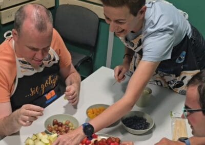 Cztery osoby sięgają po owoce w celu przygotowania szaszłyków