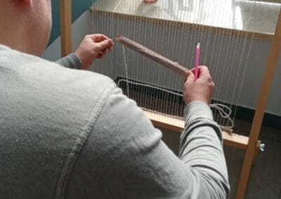 Mężczyzna tka na ramce tkackiej