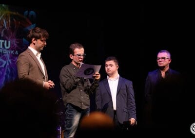 Na zdjęciu widocznych jest czterech mężczyzn - dwaj prowadzący galę prezentacji kalendarza "Barwy Sportu okiem Skowronka", prezes Stowarzyszenia Daj mi czas oraz podopieczny tego stowarzyszenia, który czyta tekst.