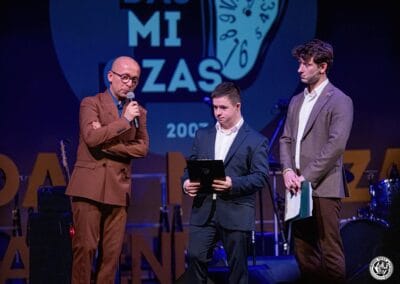 Na zdjęciu widoczni są trzej mężczyźni - prowadzący galę prezentacji kalendarza "Barwy Sportu okiem Skowronka" oraz fotograf - Grzegorz Skowronek. Te osoby stoją na scenie teatralnej.